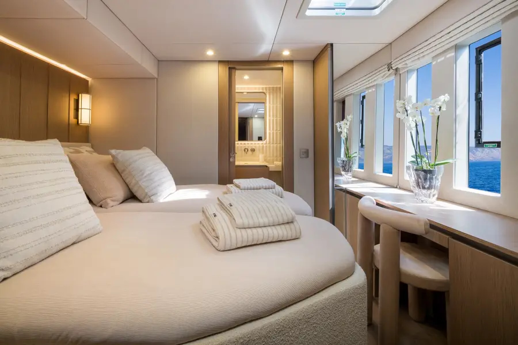 A guest cabin aboard Midori with sea-level windows and pale linen